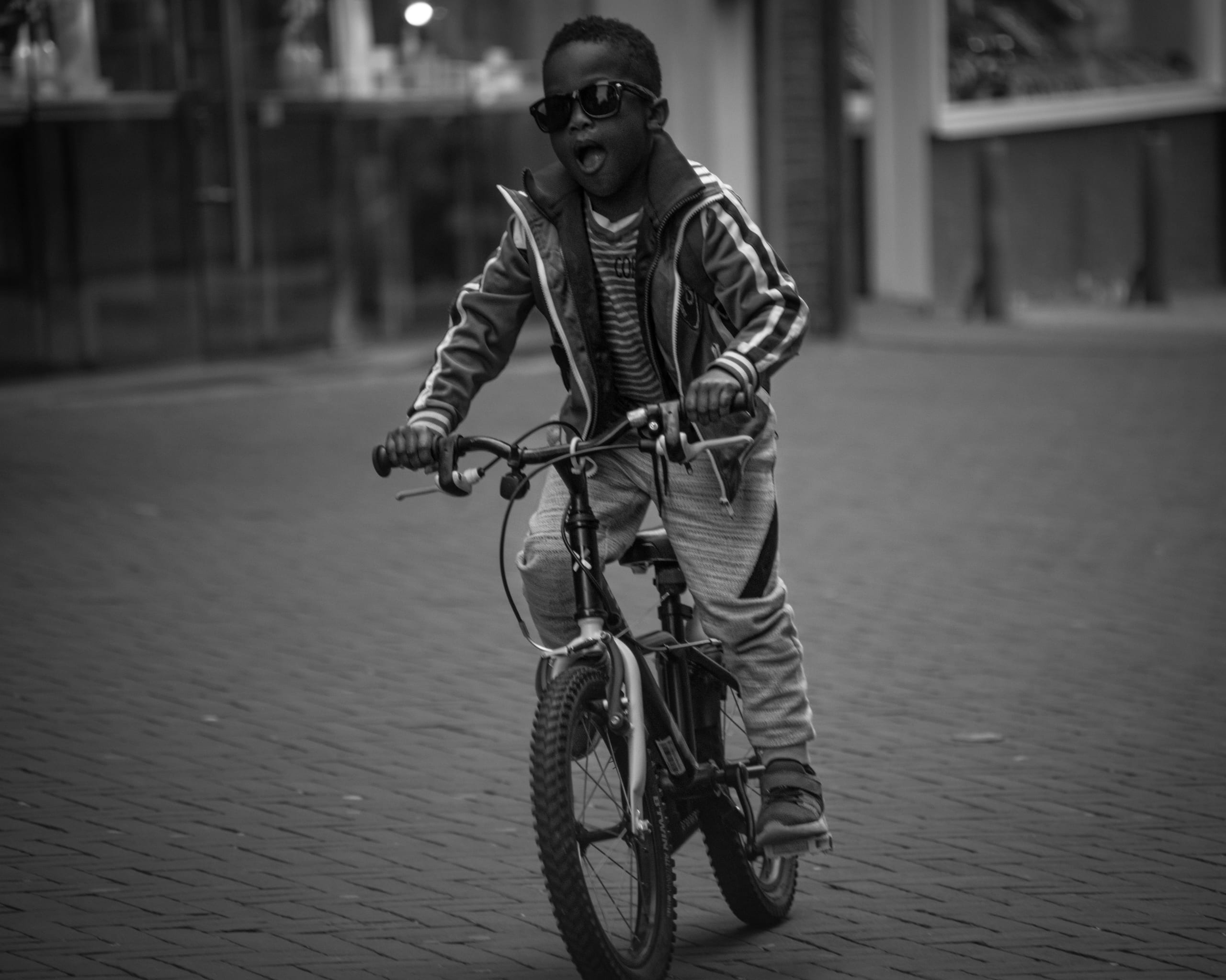 Black-and-white street photograph: a boy on a bicycle